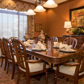 A beautifully arranged dining room featuring a wooden table set for a meal, illuminated by soft lighting.