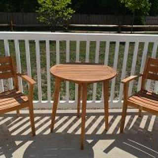 Wooden patio furniture set comprising a small table and two chairs on a deck.