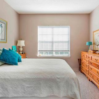 A cozy bedroom with a bed, dresser, and window letting in natural light.