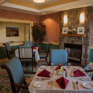 An elegantly set dining room with a fireplace and classic decor.
