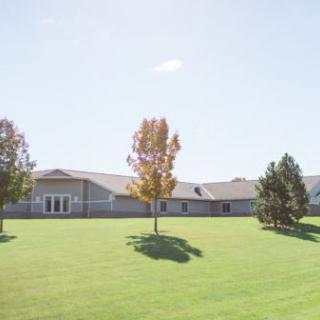 A serene view of a building surrounded by lush green grass and trees on a sunny day.