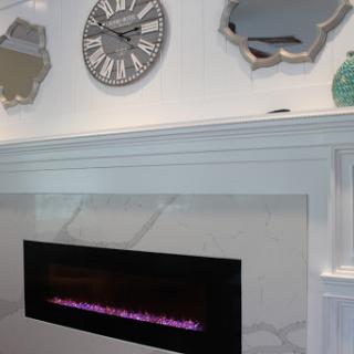 A modern living room featuring an electric fireplace, stylish mirrors, and a contemporary wall clock.