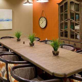 A well-decorated conference room with a large table, chairs, and decorative elements such as plants, a clock, and artwork.