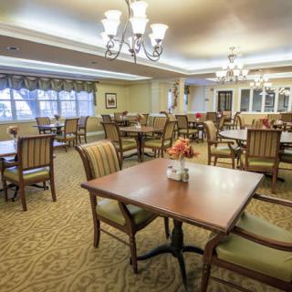An elegant dining room with neatly arranged tables and chairs, featuring warm lighting and a cozy atmosphere.