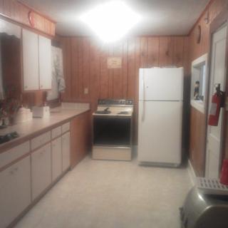 A retro kitchen with wood paneling, featuring a refrigerator and stove.