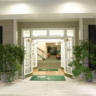 Entrance to a building with open double doors and green plants on either side.