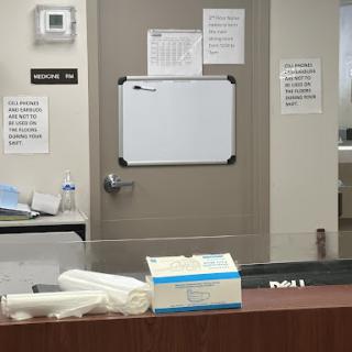 A view of an office area featuring a door, a whiteboard, and various documents on a desk.