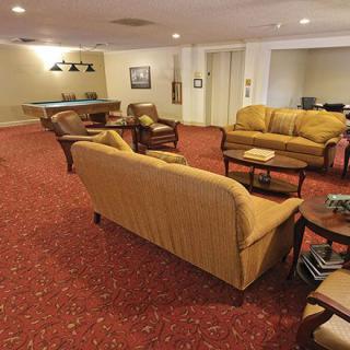 A cozy lounge area with sofas, chairs, and a coffee table on a red carpeted floor.