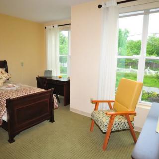 A cozy bedroom with a single bed, desk, and a chair by the window.