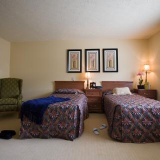 A cozy bedroom with twin beds, lamps, and decorative artwork above the headboards.