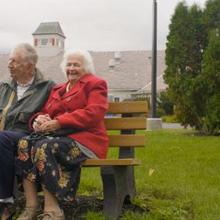 A cheerful senior couple enjoying their time together on a park bench.