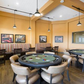 A cozy poker room with card tables, leather chairs, and warm lighting.