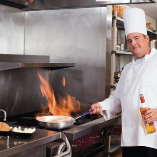 A chef expertly cooking with flames in a professional kitchen.