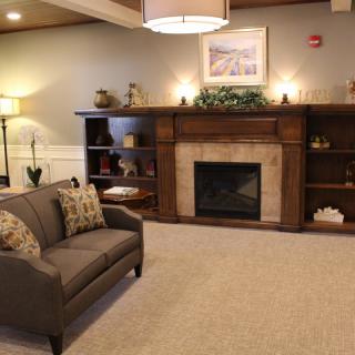 A cozy living room featuring a fireplace, sofa, and decorative shelves.