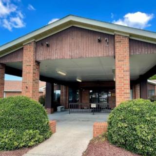 Entrance to a brick building with a covered walkway and surrounding bushes.