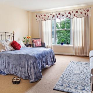 A cozy bedroom with a bed, window, and carpeted floor.