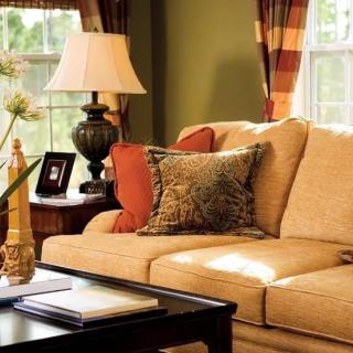A cozy living room with a beige sofa, decorative pillows, and a coffee table adorned with books and a lamp.