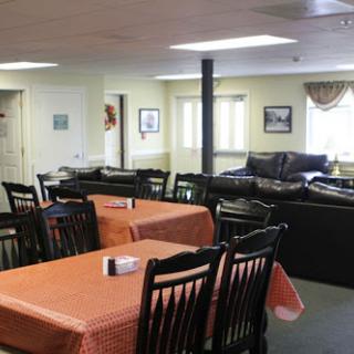 A cozy dining area with tables set for meals, featuring light-colored walls and comfortable seating.