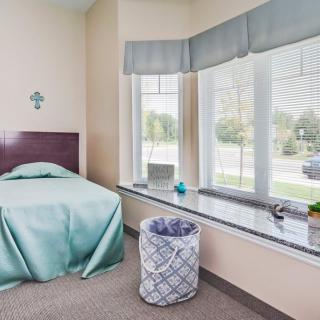 A minimalist bedroom with a single bed and large windows allowing natural light.