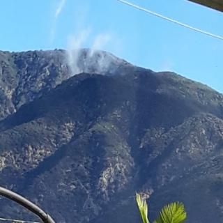 A scenic view of mountains with wisps of smoke against a clear blue sky.