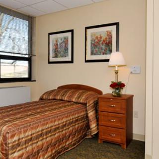 A cozy bedroom with a single bed and wooden furniture, featuring two pieces of artwork on the wall.