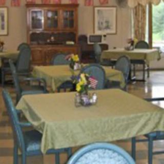 A cozy dining room with neatly arranged tables and chairs, featuring small floral centerpieces.