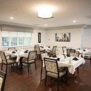 A neatly arranged dining room with elegantly set tables and chairs.