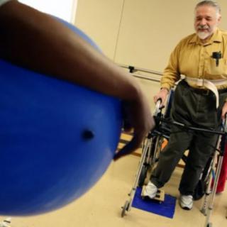 A therapy session involving a patient using a walker and an exercise ball.