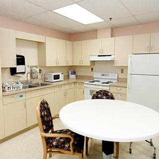 A modern kitchen setup with light-colored cabinets and a round table.