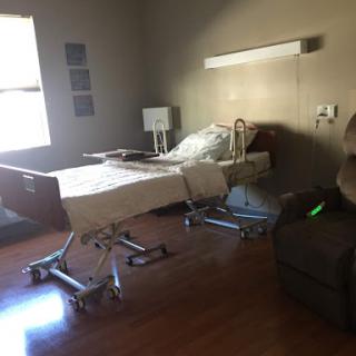A well-equipped hospital room featuring a bed, a comfortable chair, and natural light.