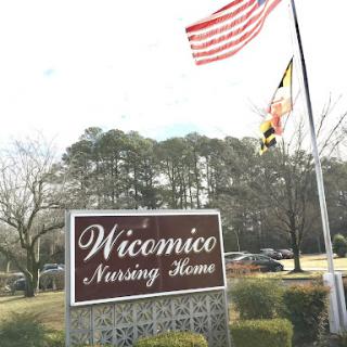 The entrance sign of Wicomico Nursing Home, featuring the American and Maryland flags.