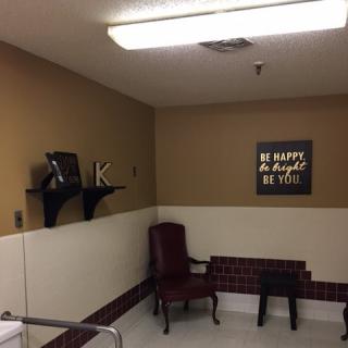 A cozy waiting area featuring a comfortable chair, a bench, and inspirational wall decor.
