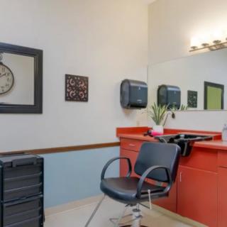 A tidy hair salon setup featuring a styling chair, mirror, and wall clock.
