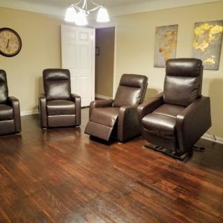A cozy living room with four recliner chairs arranged on a hardwood floor.