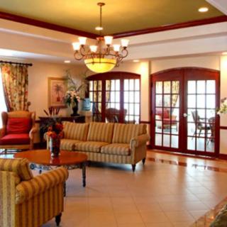 A spacious living room featuring elegant furniture, a chandelier, and large windows with curtains.