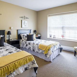 A cozy bedroom featuring twin beds with decorative bedding, a large window, and stylish interior decor.