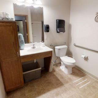 A handicap-accessible bathroom featuring a sink, toilet, and grab bars for ease of use.