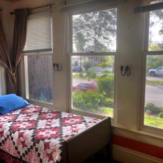 A cozy bedroom with a quilt-covered bed and large windows letting in natural light.