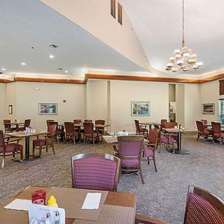 A spacious dining area with multiple tables and chairs, featuring a chandelier and wall art.