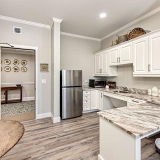 A modern kitchen featuring white cabinets, stainless steel appliances, marble countertops, and wood flooring.