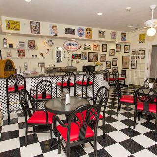 A vintage-style diner with checkered flooring and red chairs, featuring retro decor.