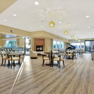 A spacious modern interior with dining tables, a piano, and a fireplace.