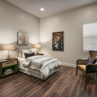 A cozy bedroom with modern decor and wooden flooring.