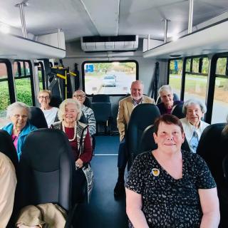 A group of elderly passengers seated inside a bus.