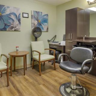A cozy salon interior with chairs, a hairdryer, and wall artwork.