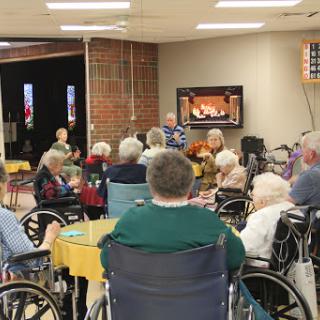 Residents enjoy a musical performance at a nursing home, fostering community and connection.