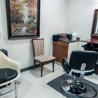 A small salon interior with chairs, a mirror, and a painting on the wall.
