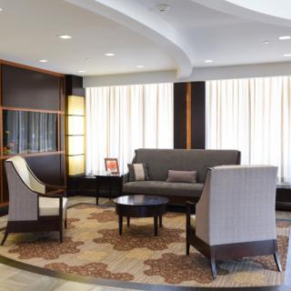 A modern lobby area featuring a sofa, chairs, and a coffee table on a patterned carpet.