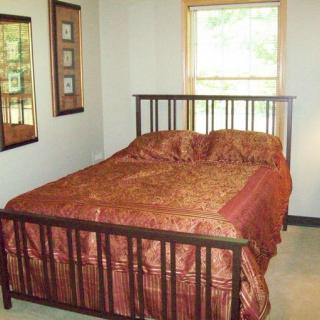 A cozy bedroom with a brown bedspread and framed artwork on the walls.