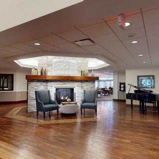 A modern lobby with a cozy seating area, featuring a fireplace and a piano.